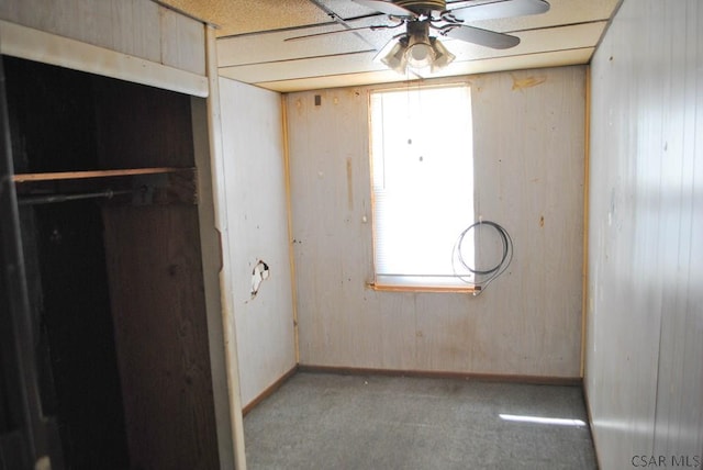 unfurnished bedroom with carpet floors, ceiling fan, and wood walls