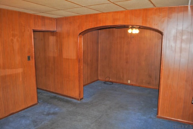 unfurnished room featuring wooden walls and dark colored carpet