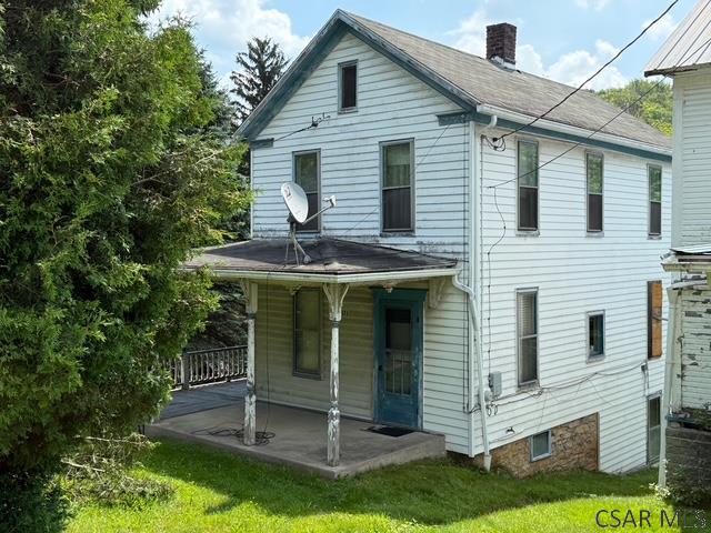 671 Listie Rd, Listie, PA 15549 - rear view of property with a chimney, covered porch, a yard, and roof with shingles