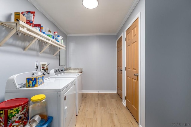 washroom featuring washing machine and dryer, ornamental molding, and light hardwood / wood-style flooring