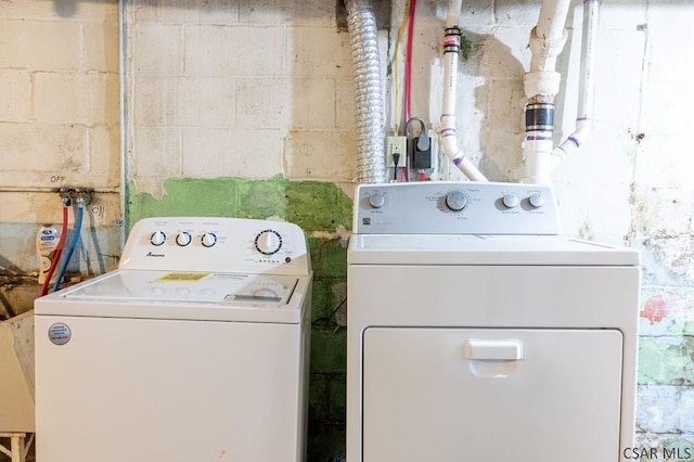 clothes washing area featuring laundry area, concrete block wall, and independent washer and dryer