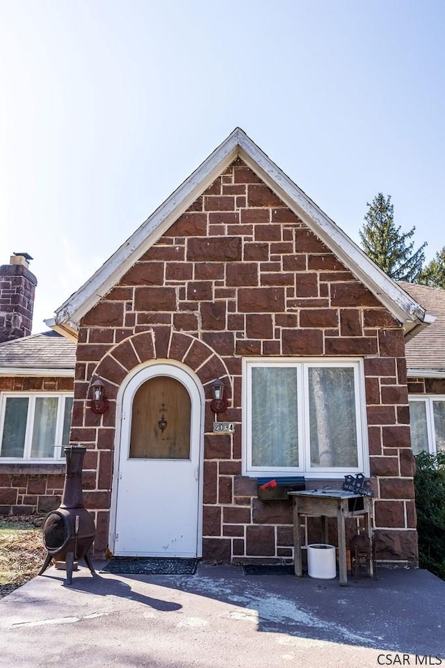 view of front facade with roof with shingles and a chimney