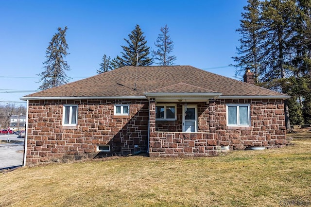 exterior space with stone siding, a lawn, a chimney, and a shingled roof