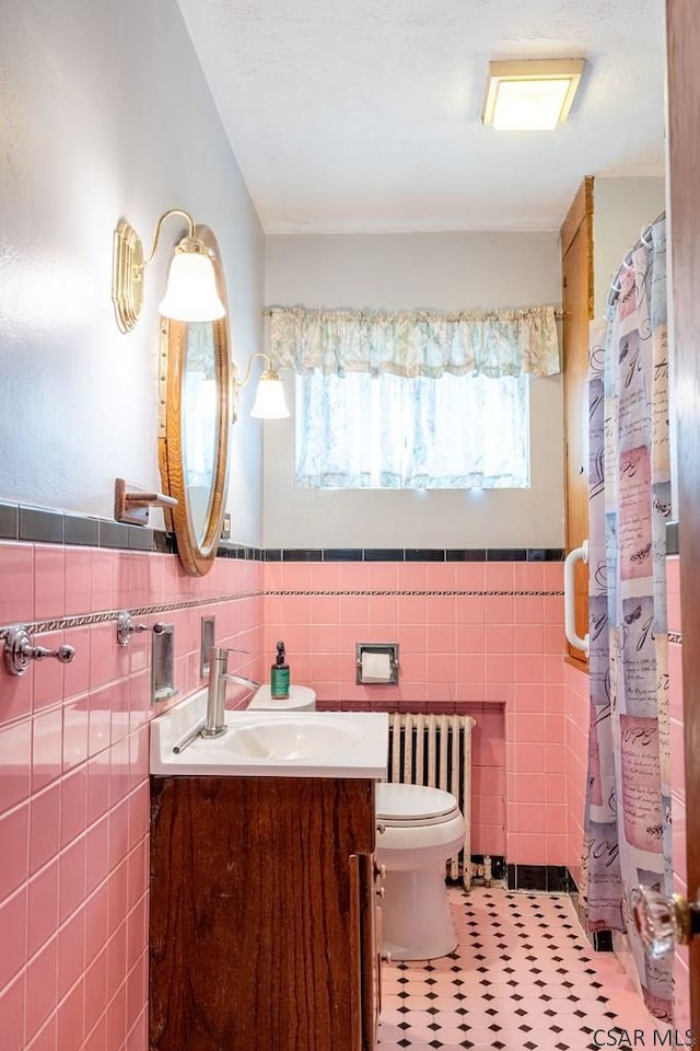 bathroom featuring a wealth of natural light, vanity, toilet, and radiator heating unit