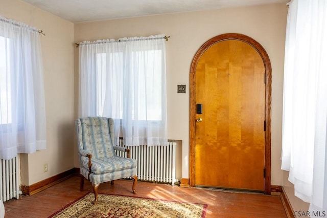 sitting room featuring radiator, wood finished floors, and baseboards