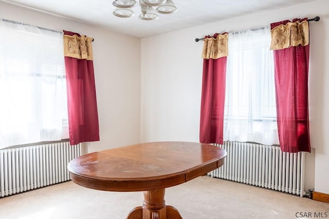 dining space with radiator heating unit, an inviting chandelier, and carpet floors