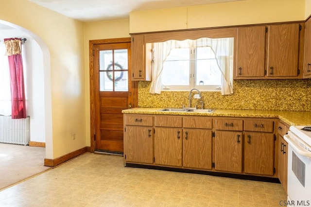 kitchen with a sink, white range with electric stovetop, radiator, decorative backsplash, and light floors