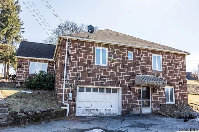 view of front of property featuring an attached garage and a shingled roof