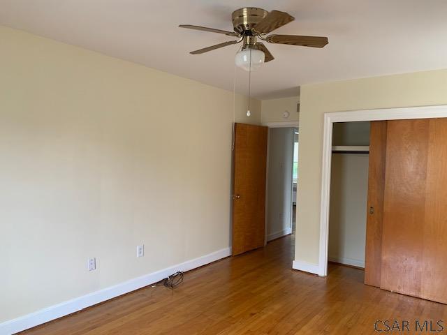 unfurnished bedroom with wood-type flooring, a closet, and ceiling fan