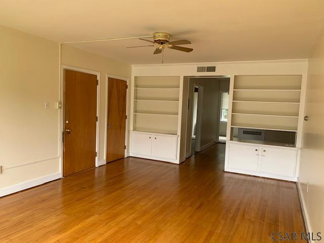 unfurnished living room featuring dark wood-type flooring, built in features, and ceiling fan