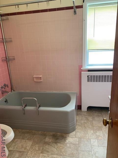 bathroom with radiator, a wealth of natural light, bathtub / shower combination, and toilet