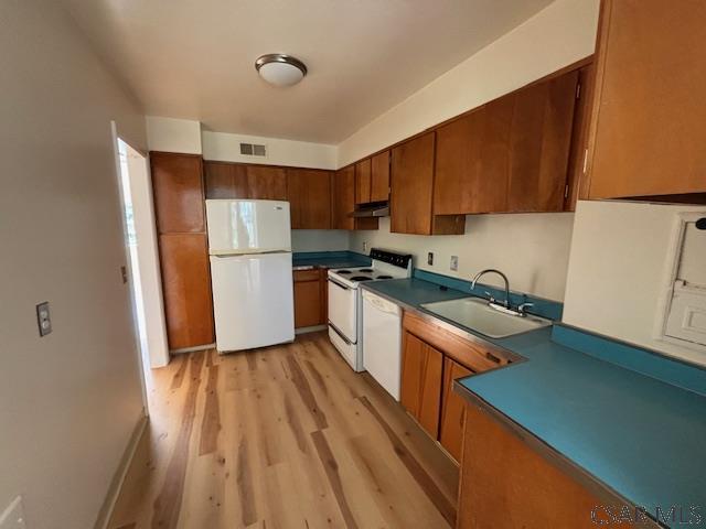 kitchen with sink, white appliances, and light hardwood / wood-style flooring