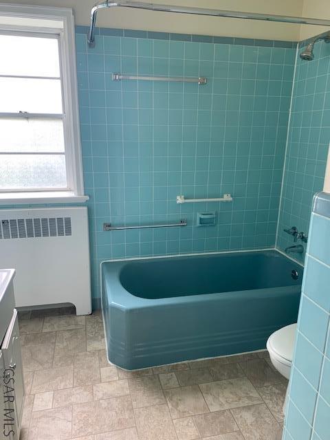 full bathroom with vanity, radiator, plenty of natural light, and tiled shower / bath