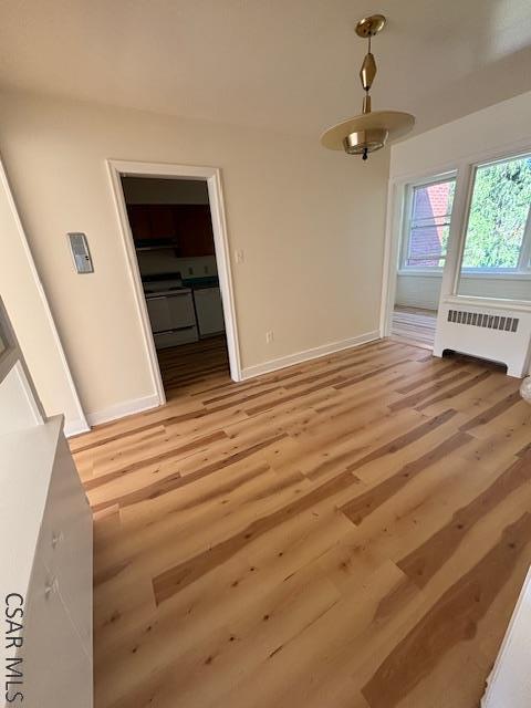 unfurnished living room featuring radiator and light wood-type flooring