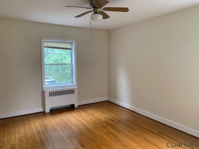 unfurnished room with light hardwood / wood-style flooring, radiator heating unit, and ceiling fan