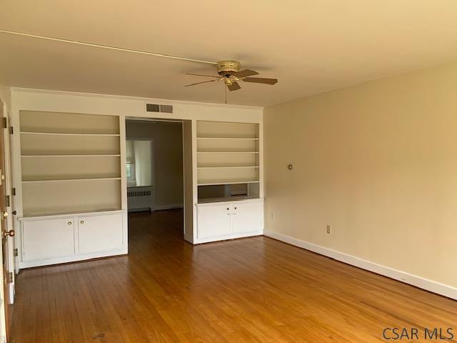 interior space featuring radiator, hardwood / wood-style flooring, built in features, and ceiling fan