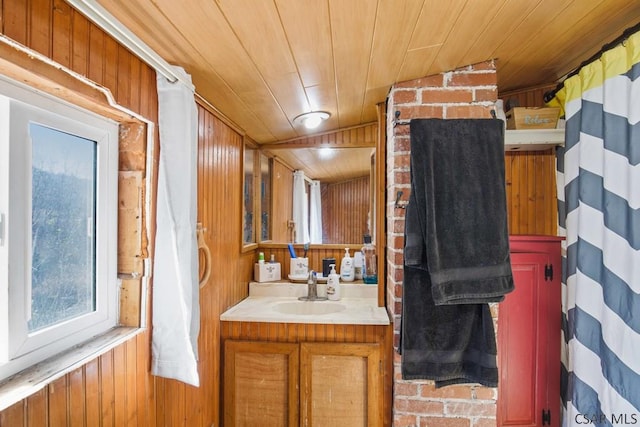 bathroom featuring vaulted ceiling, wooden walls, vanity, and wood ceiling