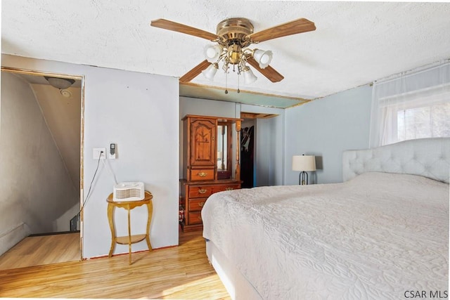 bedroom featuring ceiling fan, light hardwood / wood-style floors, and a textured ceiling