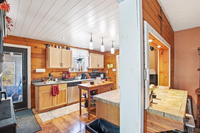 kitchen with light brown cabinetry, dishwasher, sink, and wood walls