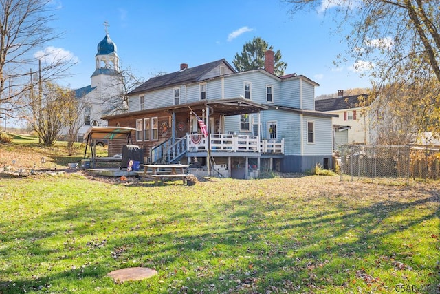 rear view of property with a wooden deck and a lawn