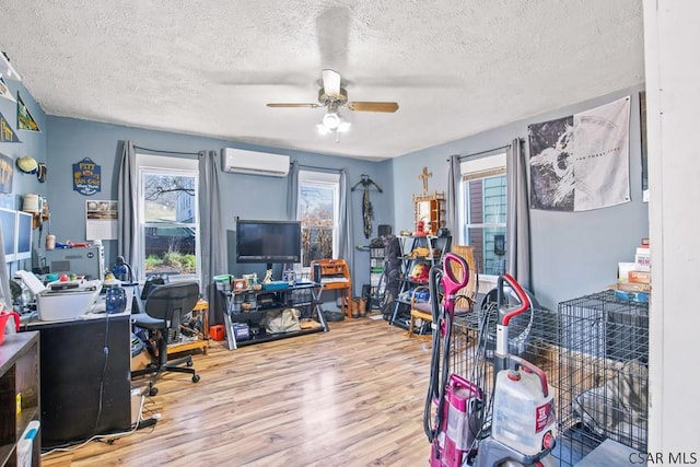 office area with ceiling fan, wood-type flooring, a wall mounted AC, and a textured ceiling