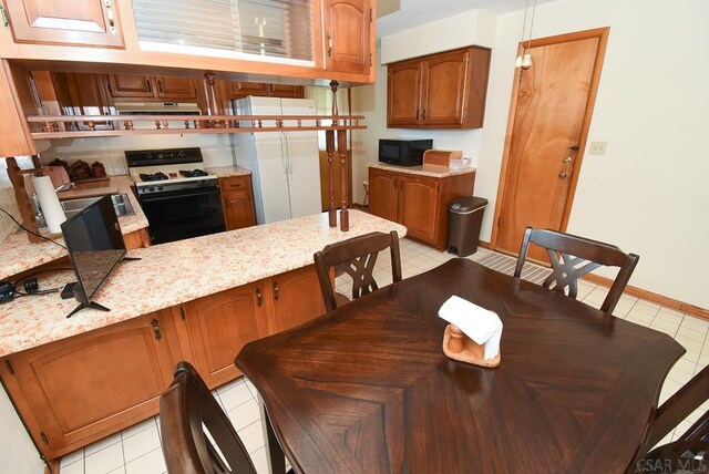 312 Furnari Ave, Johnstown, PA 15905 - kitchen featuring gas range oven, black microwave, under cabinet range hood, and light tile patterned flooring