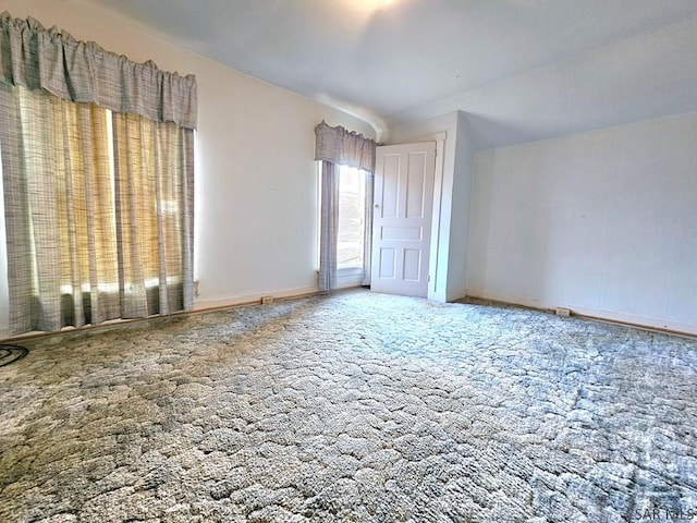 unfurnished room with vaulted ceiling, baseboards, and carpet floors