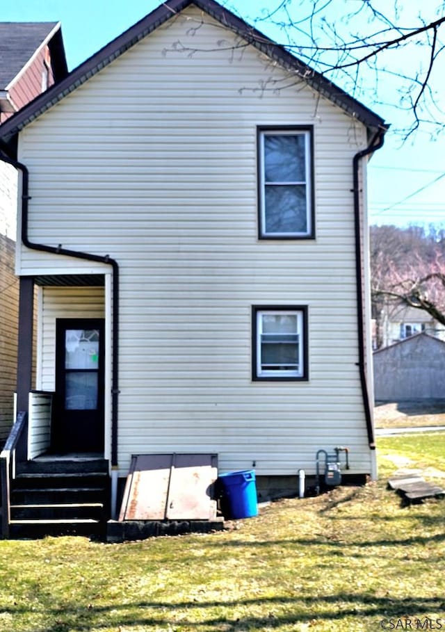 rear view of property featuring a yard and entry steps