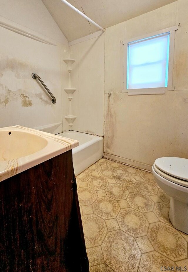 bathroom featuring bathing tub / shower combination, lofted ceiling, toilet, and vanity