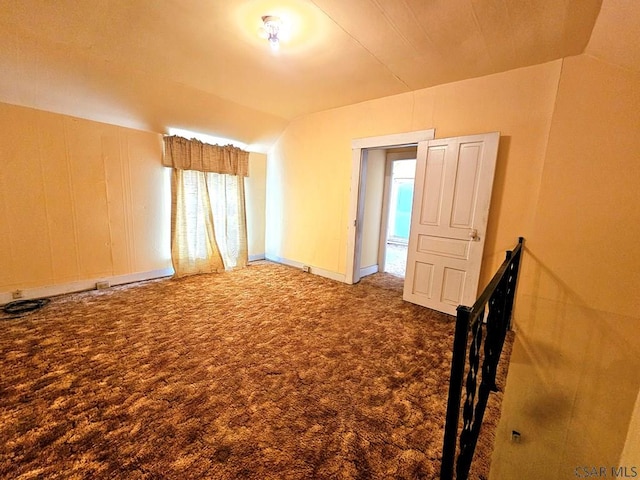spare room featuring carpet floors and vaulted ceiling