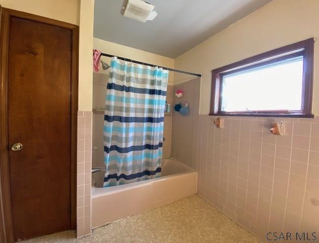 bathroom with tile walls and shower / tub combo