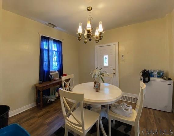 dining space featuring plenty of natural light, dark hardwood / wood-style floors, and an inviting chandelier