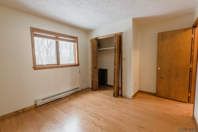 unfurnished bedroom featuring baseboard heating, a closet, a textured ceiling, and light wood-type flooring