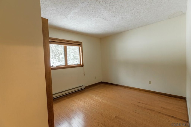 spare room with baseboard heating, light hardwood / wood-style flooring, and a textured ceiling