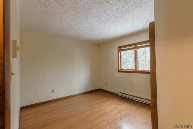 empty room featuring a baseboard radiator, a textured ceiling, and light hardwood / wood-style floors