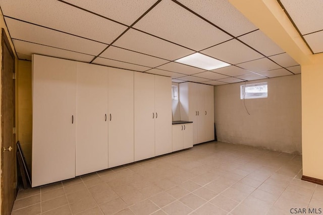 basement featuring light tile patterned floors and a drop ceiling