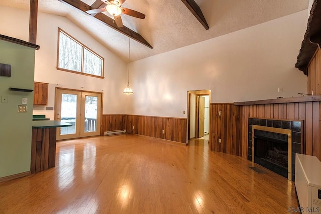 unfurnished living room with light hardwood / wood-style flooring, ceiling fan, a baseboard heating unit, a fireplace, and a textured ceiling