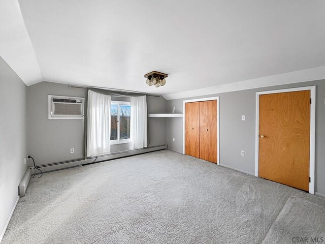 unfurnished bedroom featuring vaulted ceiling, an AC wall unit, carpet floors, and baseboard heating