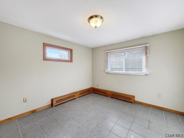 unfurnished room featuring a wealth of natural light, baseboard heating, and light tile patterned flooring