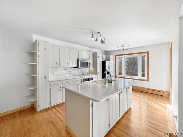 kitchen with sink, backsplash, stainless steel appliances, white cabinets, and a center island with sink