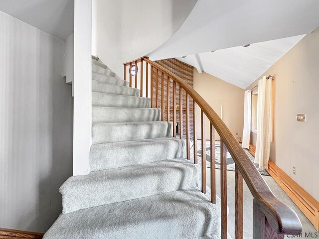 staircase with vaulted ceiling and carpet