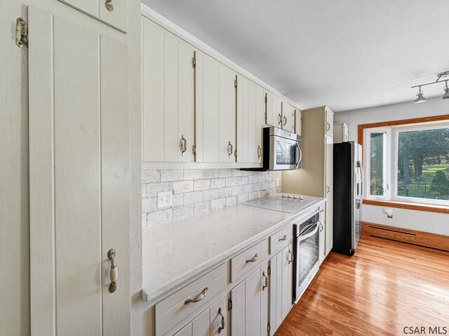 kitchen featuring tasteful backsplash, appliances with stainless steel finishes, white cabinets, and light hardwood / wood-style floors