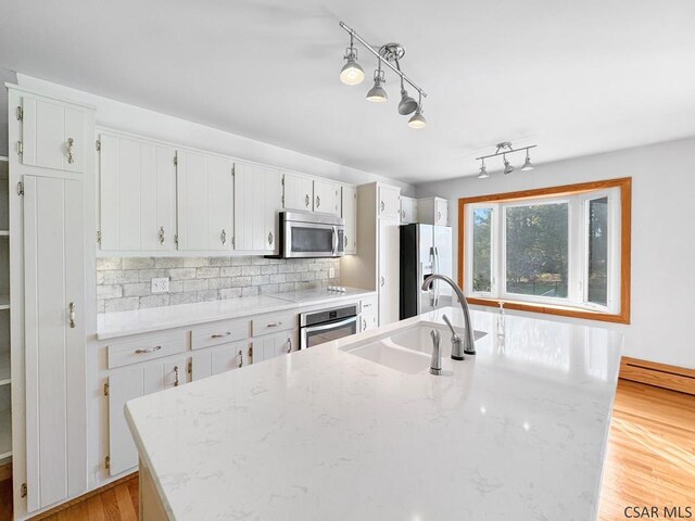 kitchen featuring sink, appliances with stainless steel finishes, light stone countertops, white cabinets, and decorative light fixtures