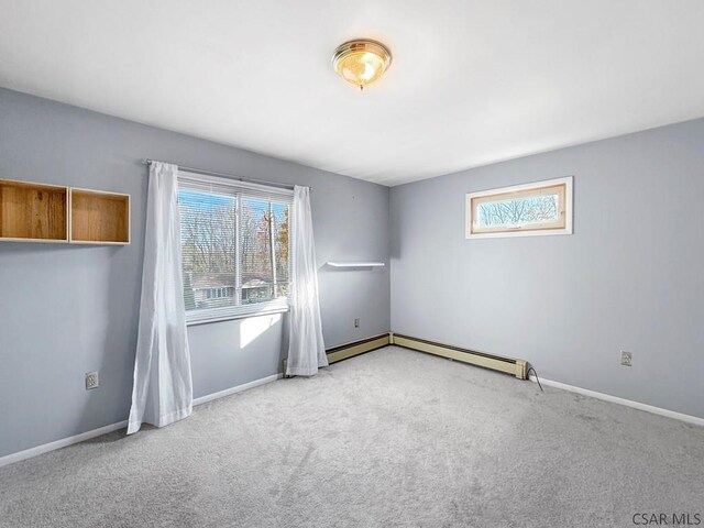 spare room featuring light carpet and a baseboard heating unit