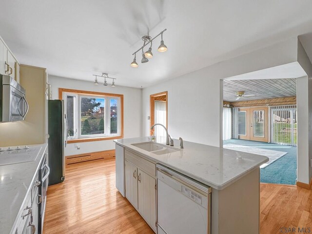 kitchen featuring appliances with stainless steel finishes, white cabinetry, sink, a kitchen island with sink, and light stone countertops