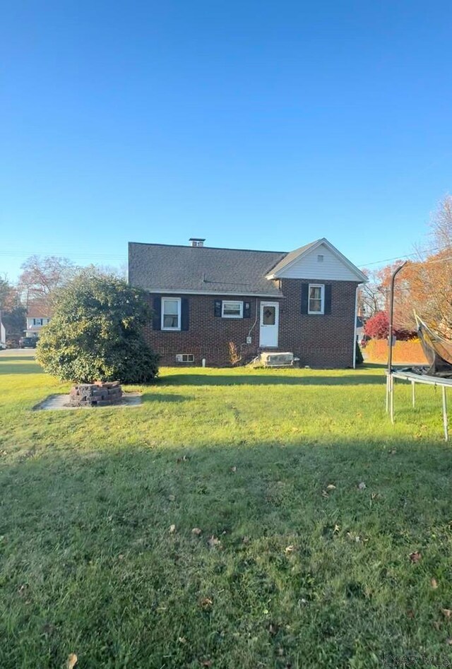 back of house featuring a yard and a trampoline