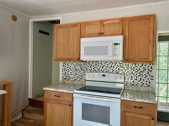 kitchen with ornamental molding, light stone countertops, a wealth of natural light, and white appliances