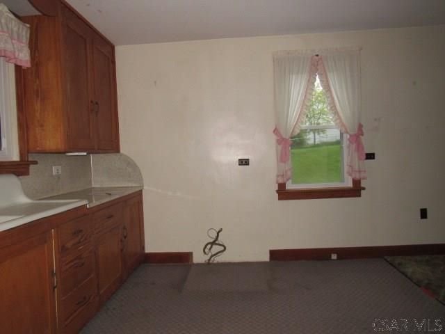 619 W Race St, Somerset, PA 15501 - kitchen with brown cabinetry, baseboards, light countertops, and light colored carpet