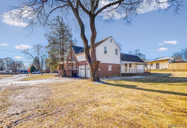 view of side of property featuring brick siding, a yard, a chimney, a porch, and a garage