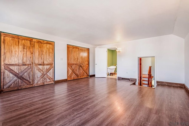 unfurnished bedroom with baseboards, vaulted ceiling, and dark wood-type flooring